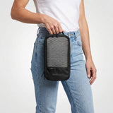 Kvinna i vit t-shirt och jeans håller en svart packkub med nätficka på framsidan.