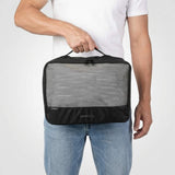 Man i vit t-shirt och jeans håller en stor svart packkub med nätficka på framsidan.