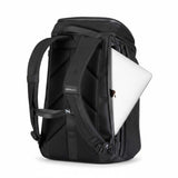 Svart ryggsäck med en silvrig laptop delvis inskjuten i sidofacket.