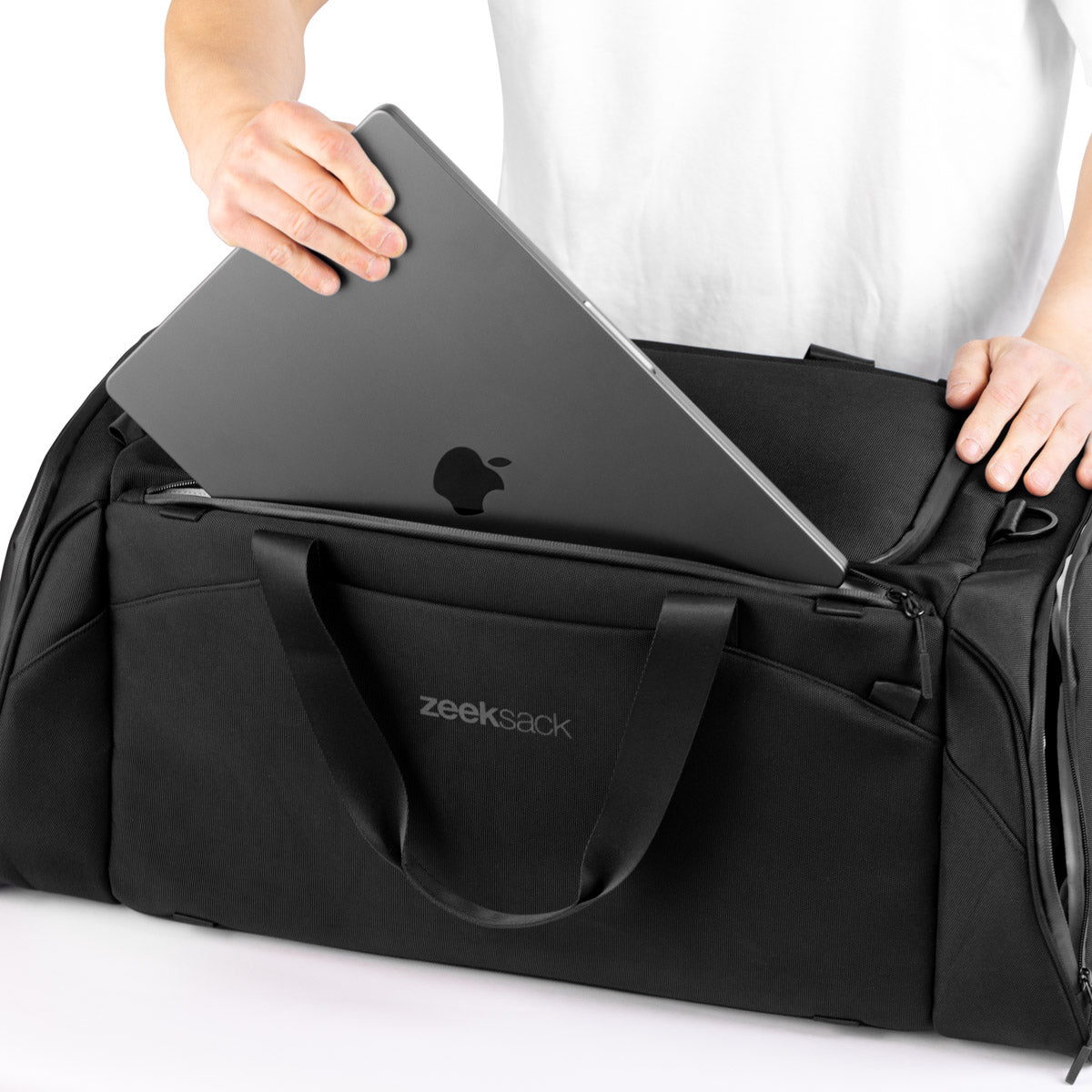 Man lägger ner laptop i separat laptopfack på duffelväska