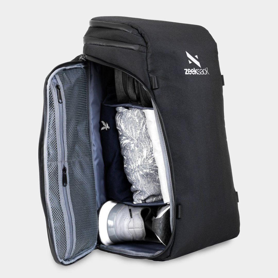 A black backpack opened from the side and packed with shoes and clothing.