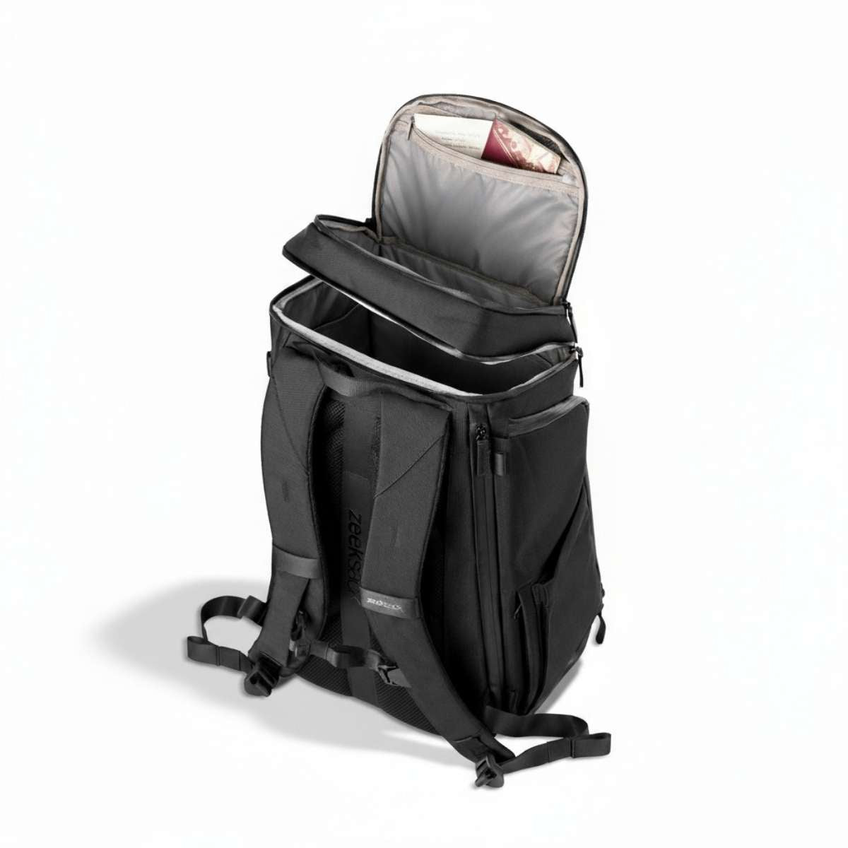 Black backpack viewed from the side, standing on the floor with the top compartment partially open.